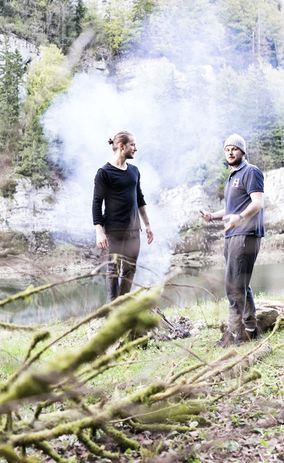 Двое мужчин стоят у костра.